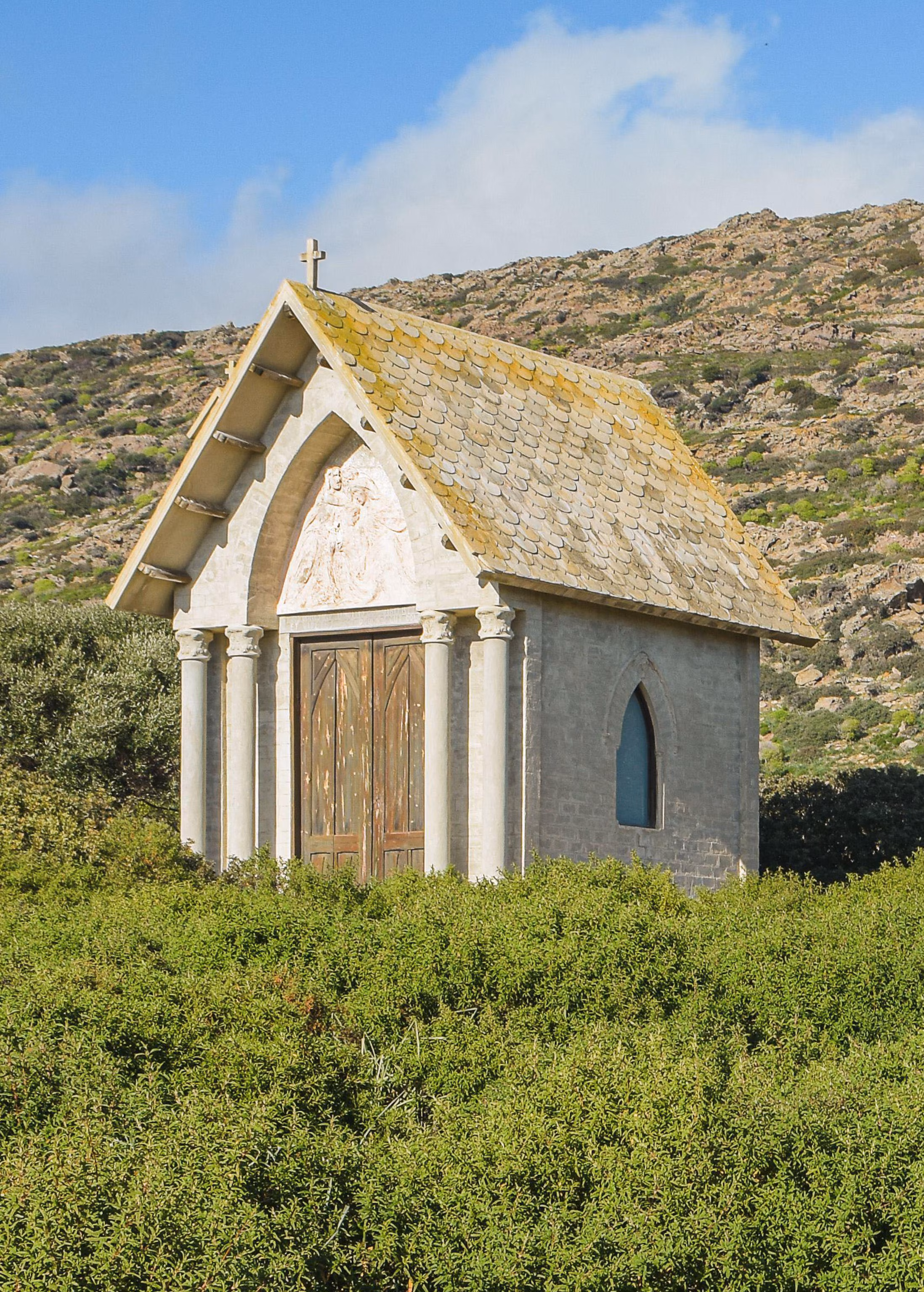 Et lille hvidt kapel sidder på toppen af en grøn bakke.