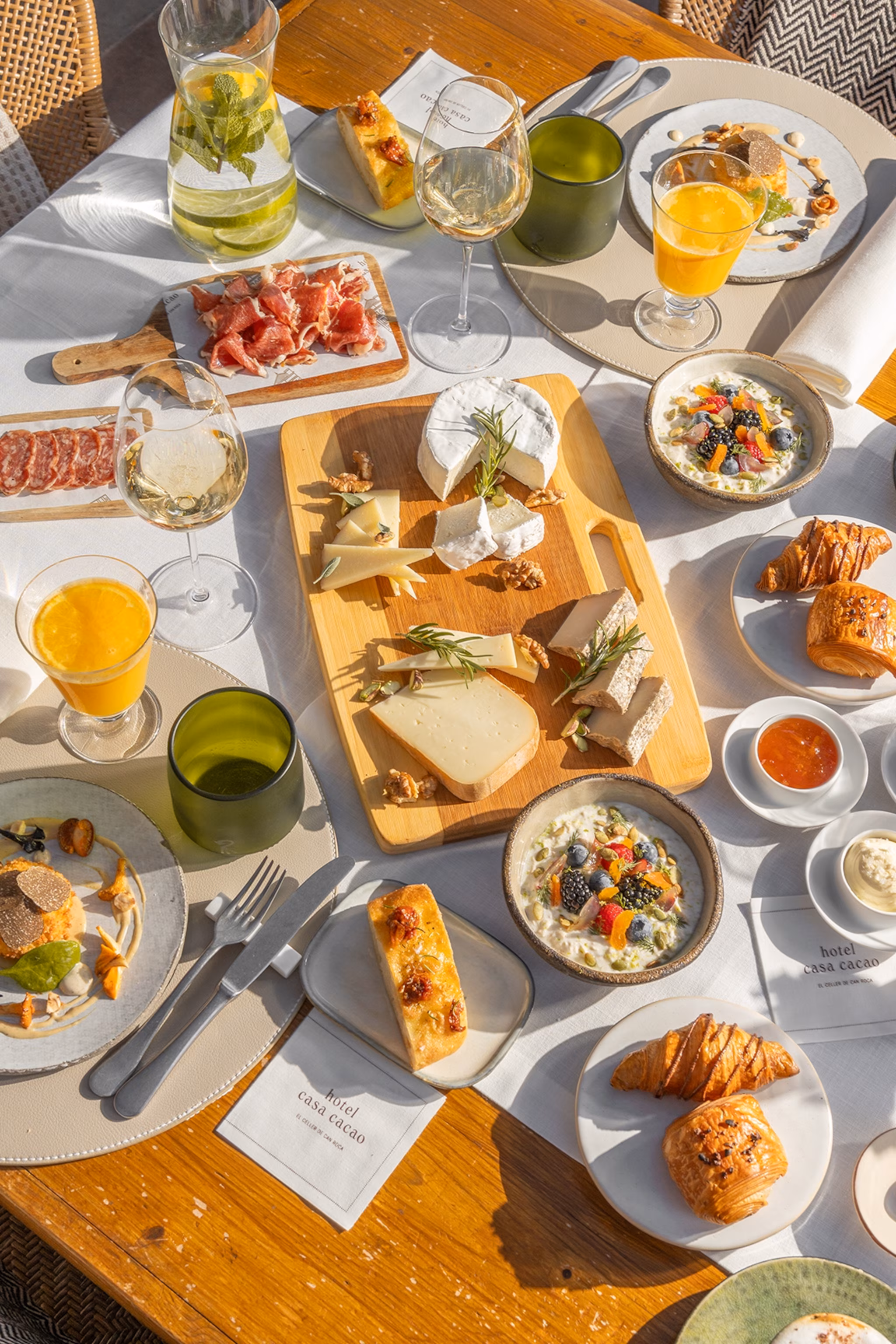 Et overdådigt morgenmadspålæg med oste, brød, smørepålæg og juice.