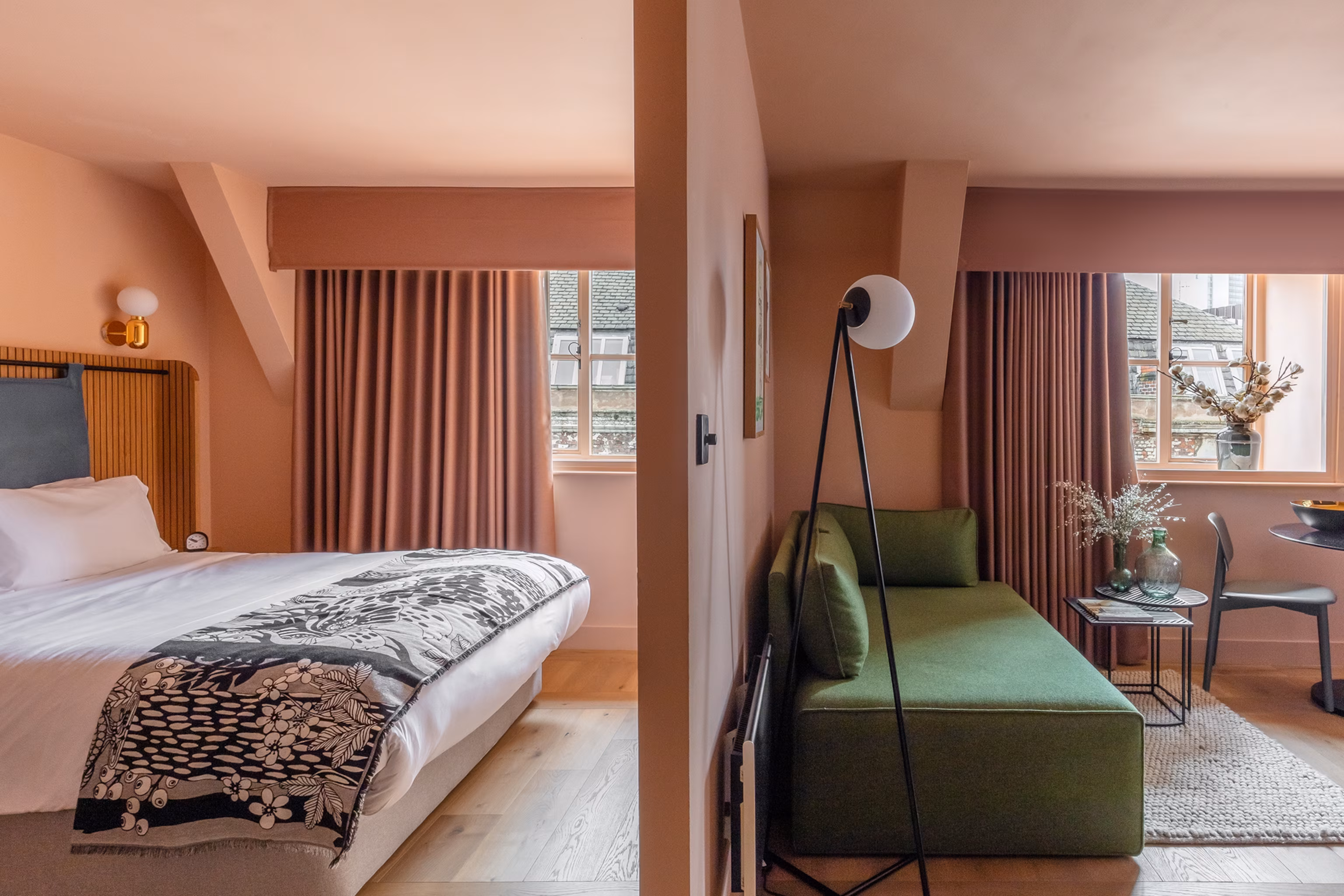 En landskabsudsigt ind i et hotelværelse med den ene side med en dobbeltseng og den anden side en stue.