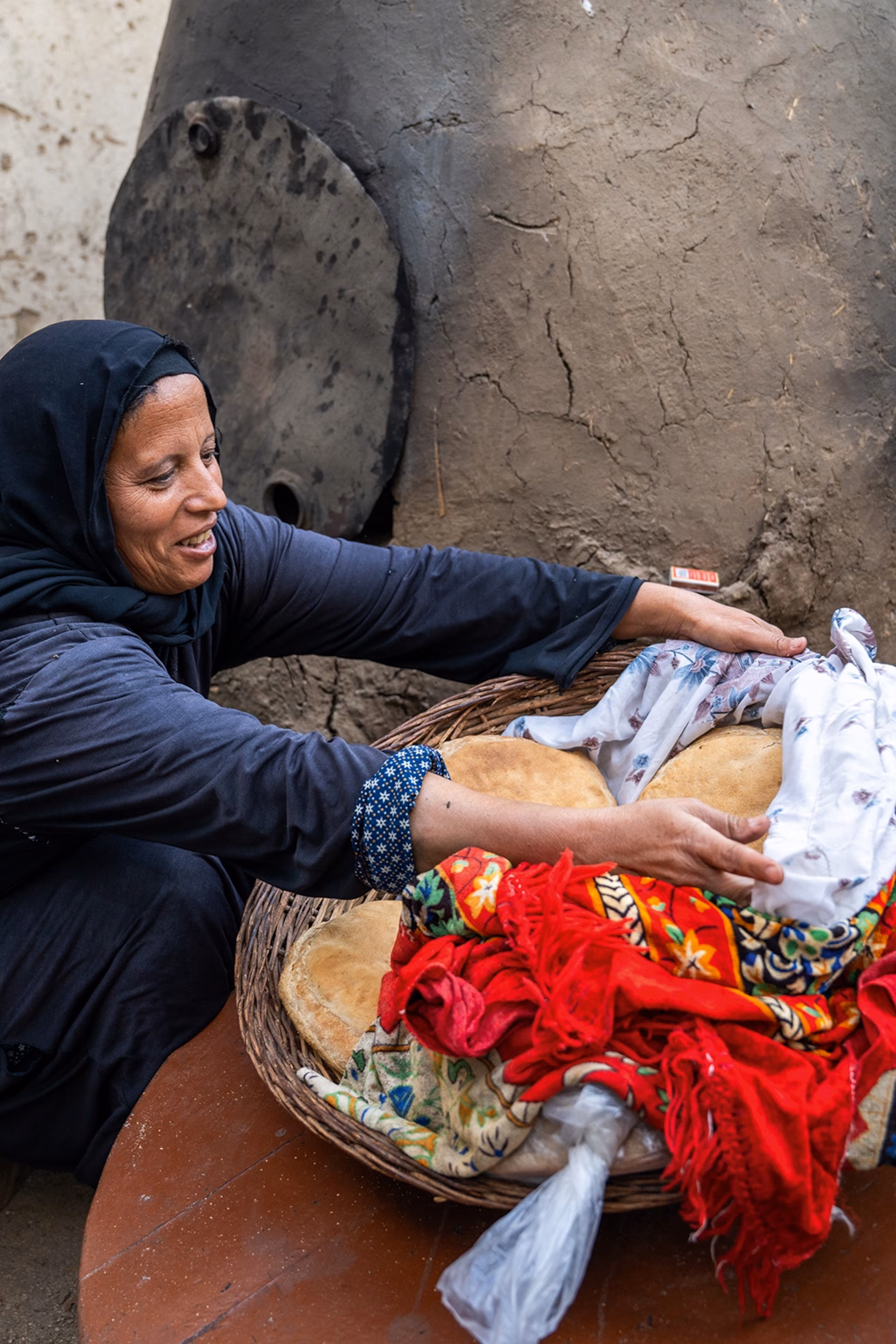 En lokal kvinde i Egypten præsenterer frisk brød i en kurv på gulvet.