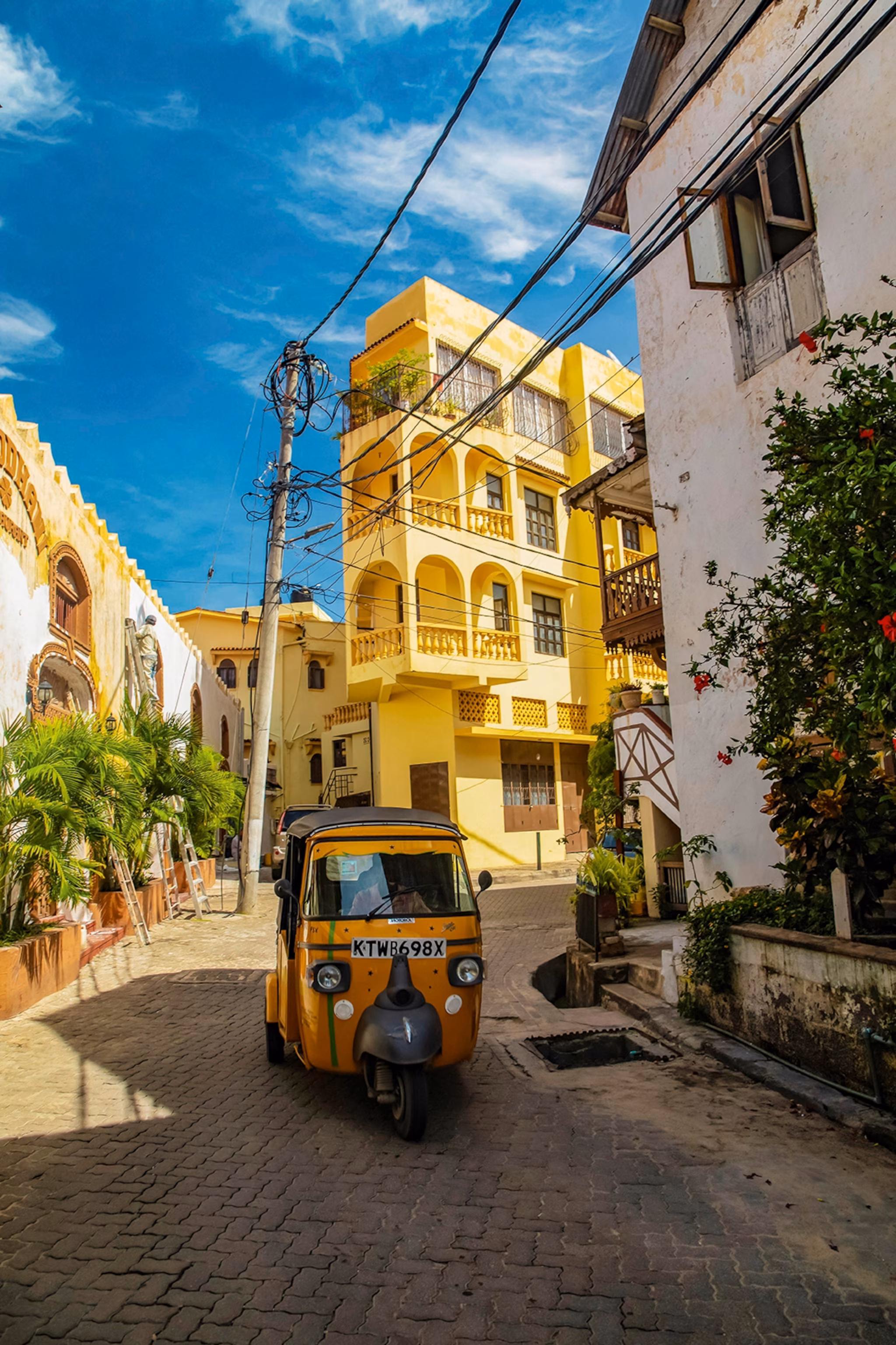 En tuk-tuk, der navigerer gennem en stille sidegade omgivet af arkitektur i europæisk stil.