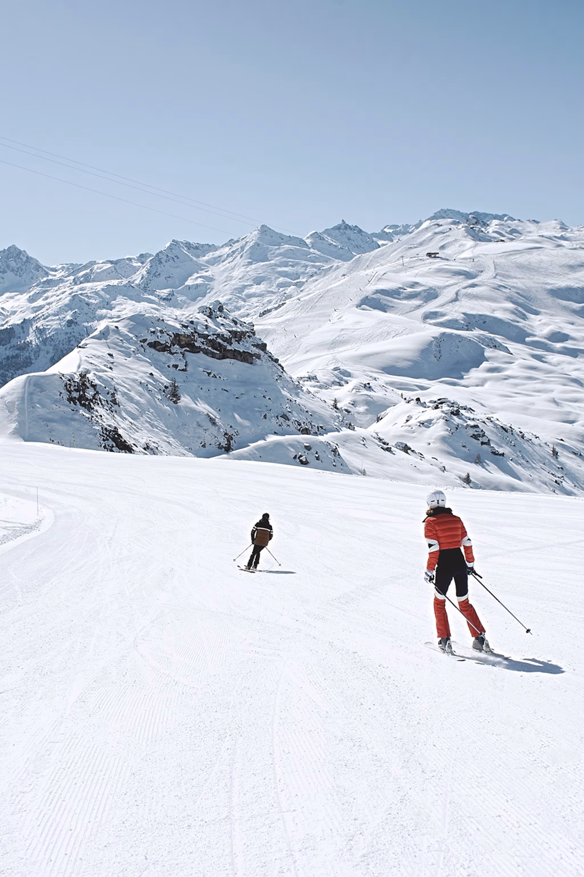 To skiløbere ned ad en stille og ren piste i de franske alper.