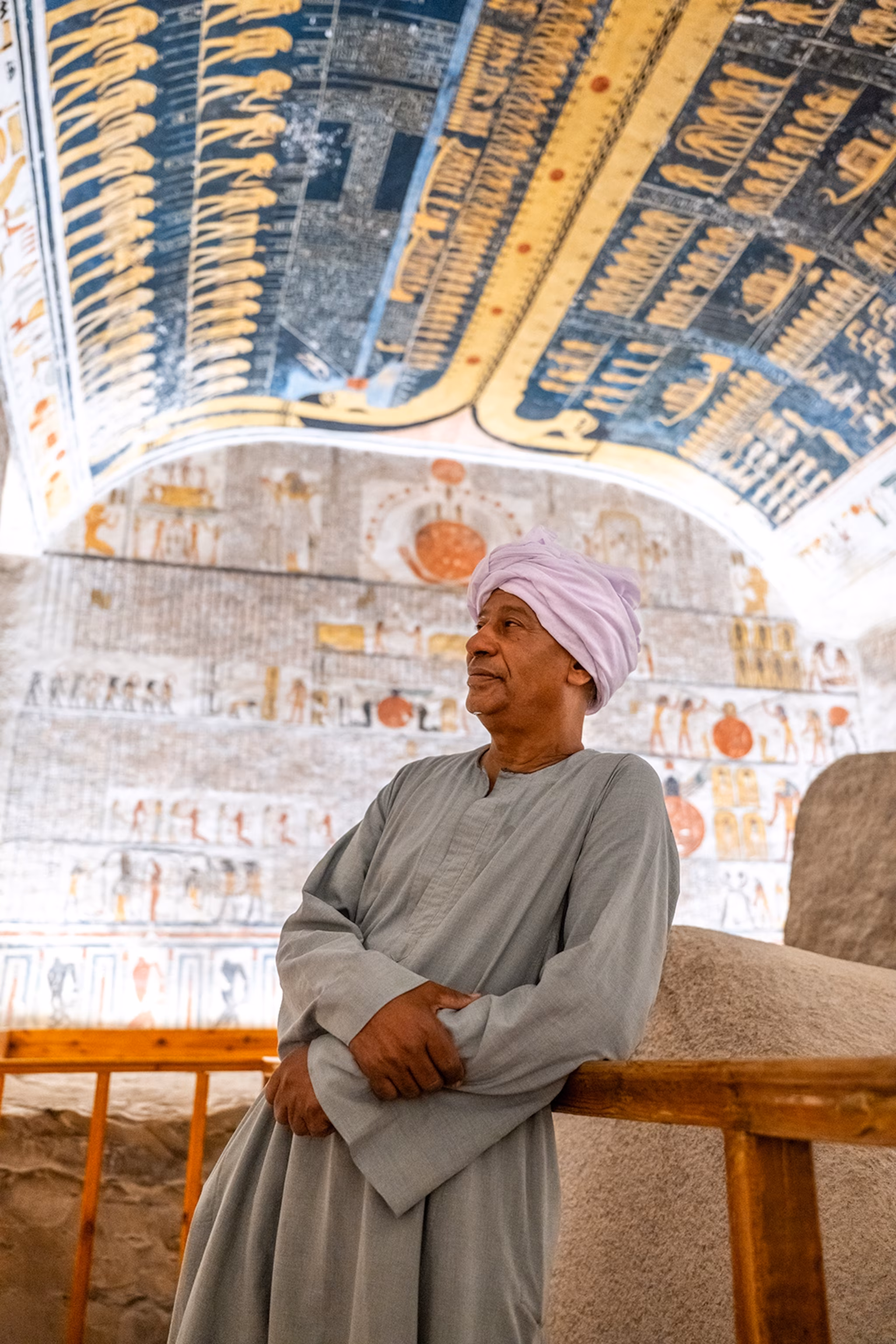 En lokal mand iført tunika og turban læner sig op ad rækværket i et rigt dekoreret tempel.